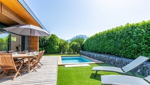 A wooden deck with a pool, lounge chairs, and a dining table with chairs. - Maison BOOA 4* - Private swimming pool & Lake nearby (Sévrier)