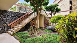 Una escalera que lleva a un edificio con un muro de piedra y un jardín con diversas plantas.