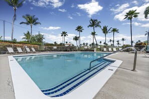 A swimming pool with lounge chairs and palm trees.
