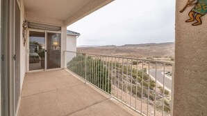 A balcony with a view of a desert landscape, a door leading to a room, and a wall-mounted sculpture.