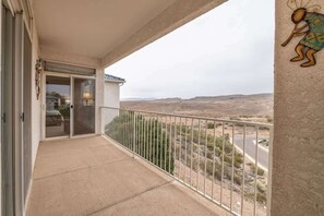 A balcony with a view of a desert landscape, a door leading to a room, and a wall-mounted sculpture.