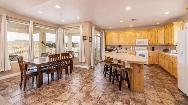 A spacious kitchen with wooden cabinets, a central island, and a dining area with chairs.