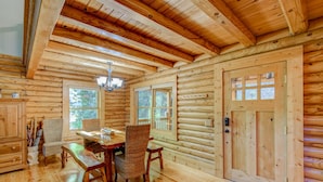 A log cabin interior with a dining area, wooden walls, and a large window. - Hideaway Homestead - Private 3BR home between Boone/ Banner Elk! Pet friendly, excellent location! (Banner Elk)