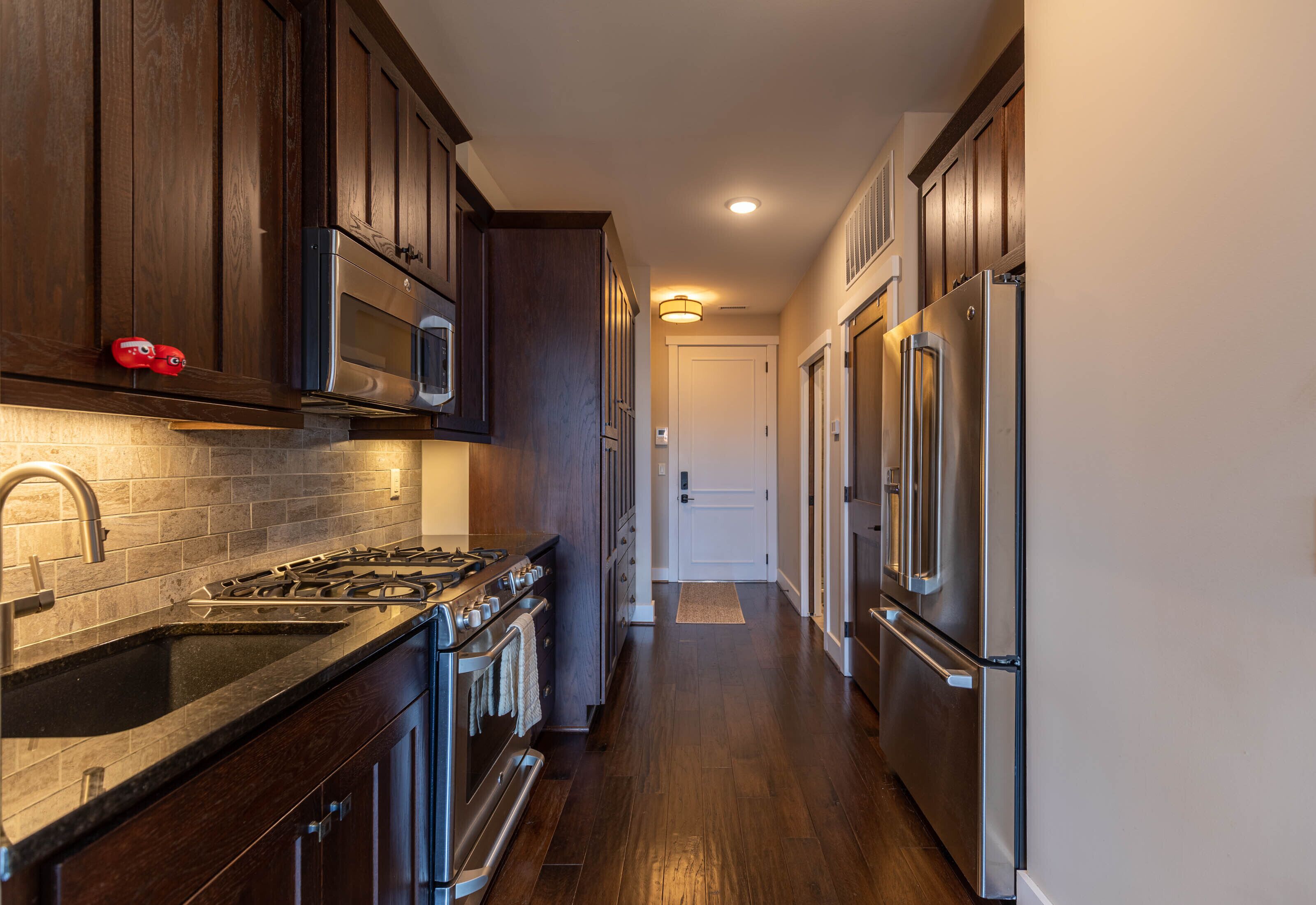 A kitchen with dark wooden cabinets, stainless steel appliances, and a tiled backsplash.