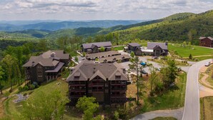 Un chalet comprenant plusieurs bâtiments, un espace de stationnement et offrant une vue sur les montagnes environnantes.