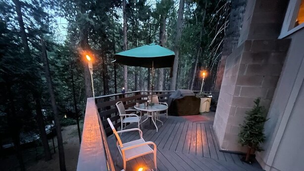 An outdoor deck with a fire pit, seating area, and a table with chairs.