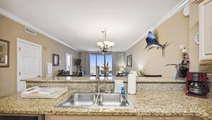 A kitchen with granite countertops, stainless steel sinks, and a ceiling fan.