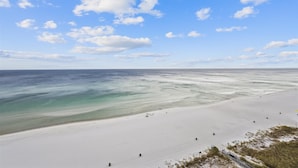 A wide beach with clear water and a sandy shore.