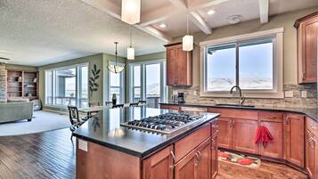 A spacious kitchen with a central island, large windows, and a view of the outdoors.
