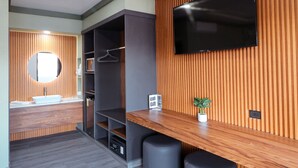 Une salle de bain moderne avec un meuble-lavabo en bois, un miroir rond, un porte-serviettes et un téléviseur encastré.