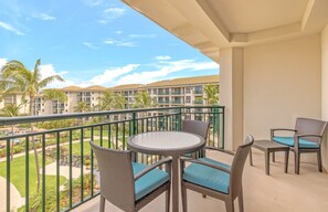 Relax on the balcony with a view of the landscaped area and pool, surrounded by palm trees.
