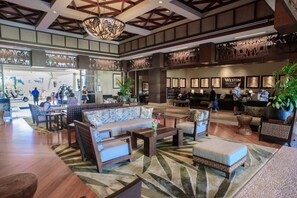 Relax in our spacious lobby, featuring a high ceiling with exposed beams, comfortable seating areas, and a beautiful chandelier.