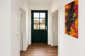 A hallway with a dark green door, white walls, and a wooden floor. - Naturferienhaus 1 - Naturferienhaus auf der Insel Rügen (Poseritz)