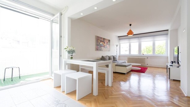 A modern living room with a white sofa, a dining table, and a red rug. - Your comfy stay in Central Sarajevo (Sarajevo)