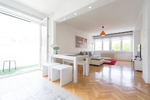 Uma sala de estar moderna com um sofá branco, uma mesa de jantar e um tapete vermelho.