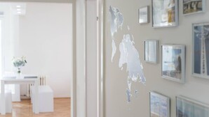 A modern interior with a minimalist design, featuring a white reception desk, framed artwork on the walls, and a large map decoration. - Your comfy stay in Central Sarajevo (Sarajevo)
