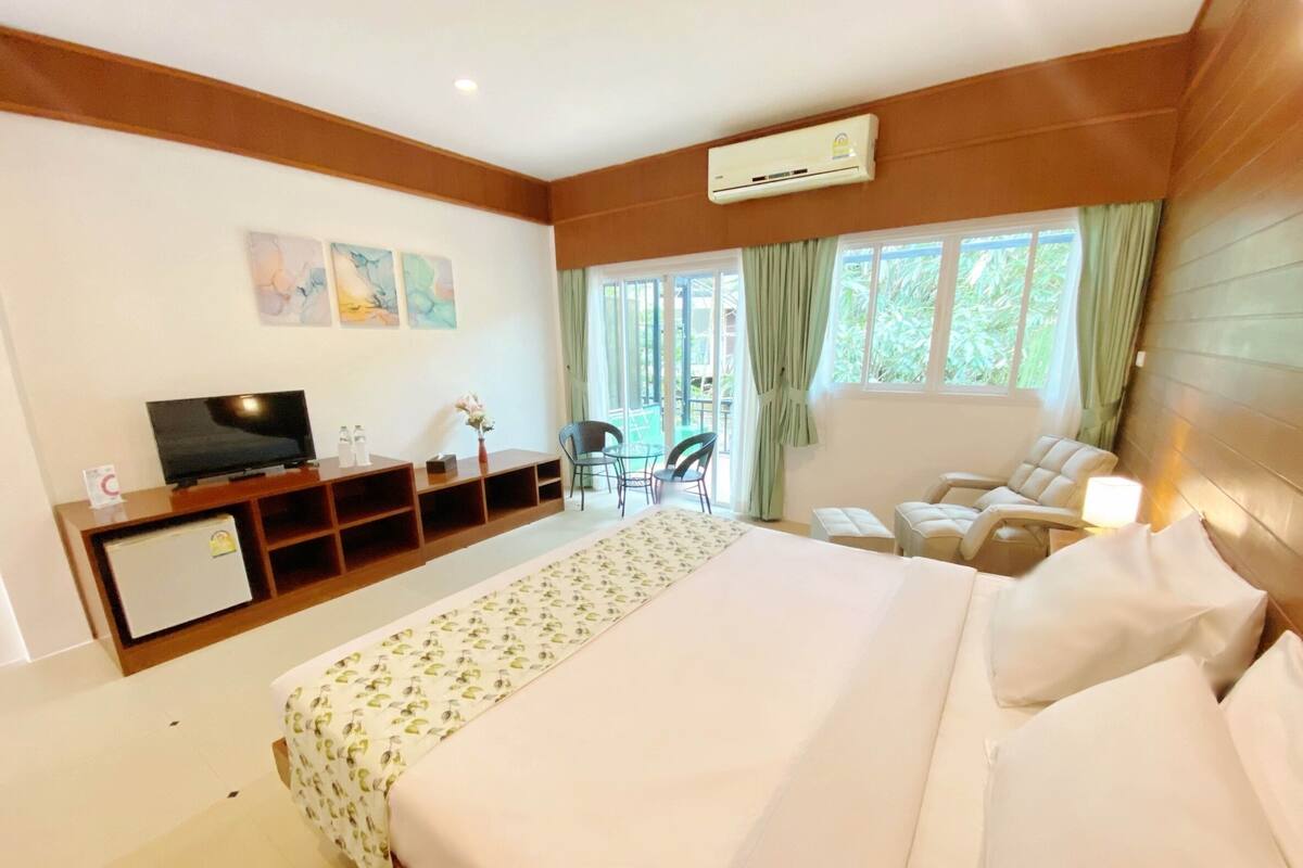 Quarto de hotel com uma cama grande, televisão, escrivaninha e uma cadeira.