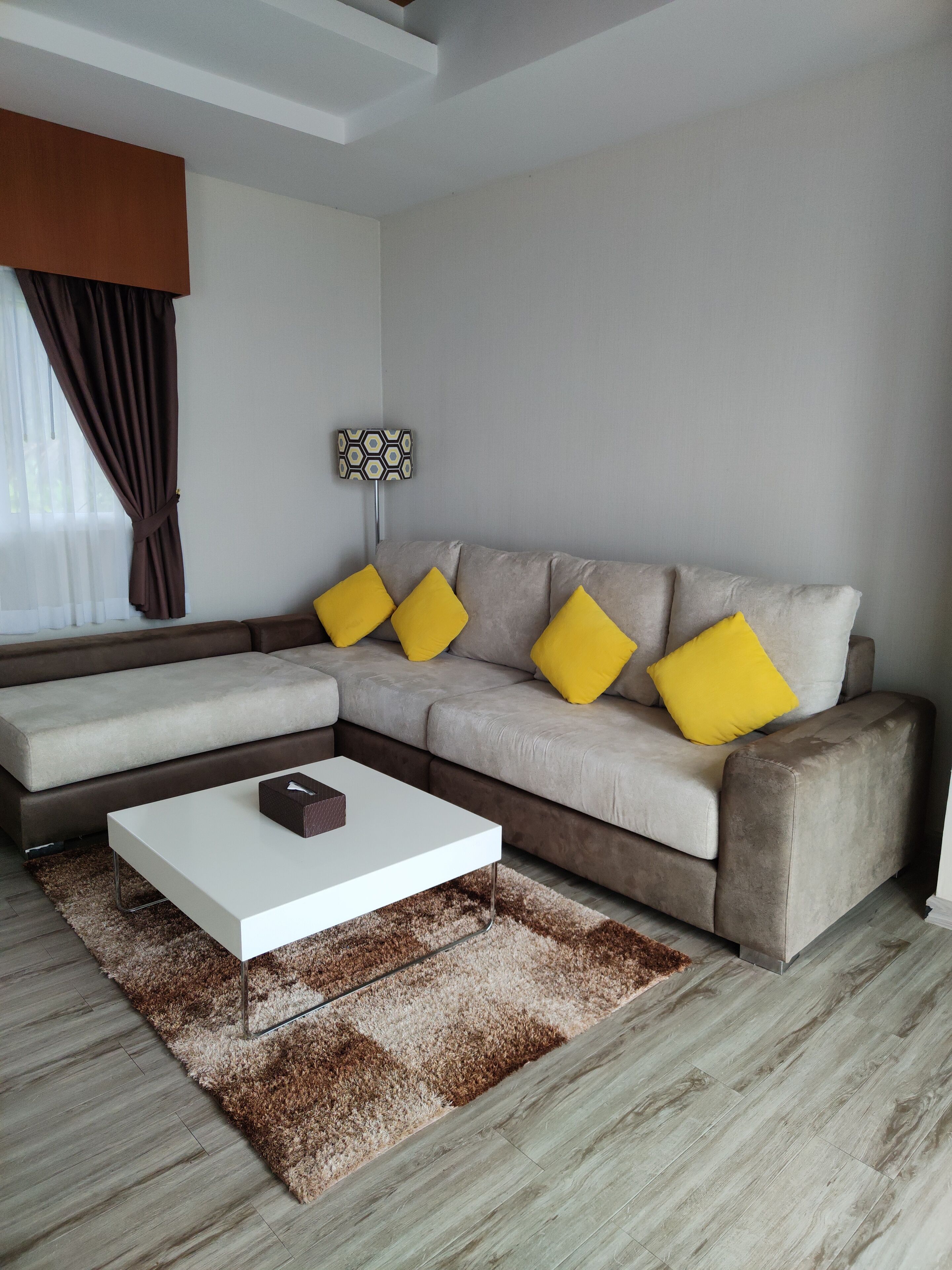 A modern living room with a sectional sofa, a white coffee table, and a patterned rug.