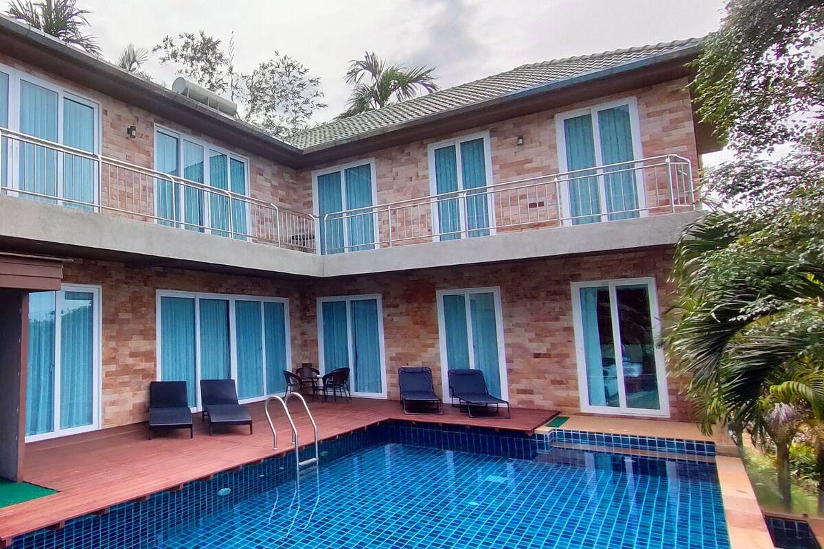 Um edifício moderno de dois andares, com piscina, janelas amplas e área de estar ao ar livre.