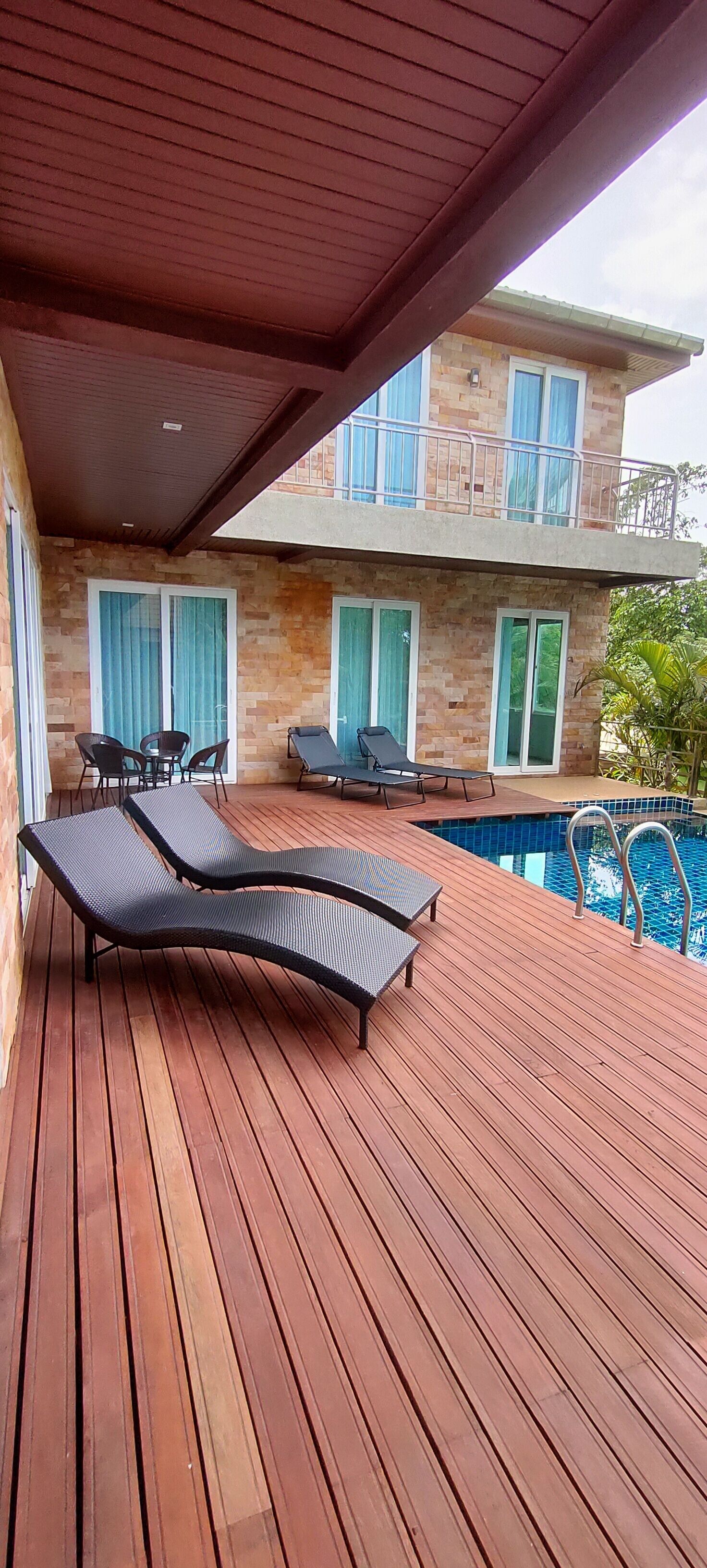 A wooden deck with lounge chairs and a pool.