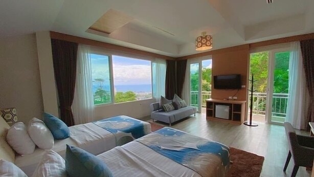 A hotel room with two beds, a sofa, a TV, and a balcony with a view. - Phuket Jungle Experience Resort (Karon)