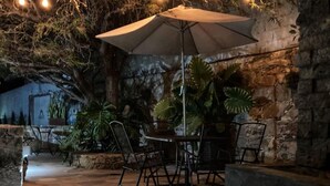 An outdoor seating area with stone walls, potted plants, and a table with chairs. - Equinoccio Peña de Bernal (Ezequiel Montes)