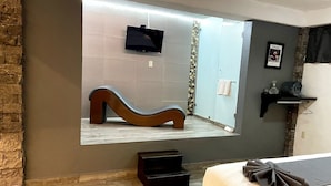 A bathroom with a large mirror, a wooden bench, a small black stool, a towel rack, and a framed picture on the wall. - Equinoccio Peña de Bernal (Ezequiel Montes)