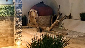 A stone pathway leading to a rustic building with a dome roof, surrounded by a landscaped garden with a planter of green plants. - Equinoccio Peña de Bernal (Ezequiel Montes)