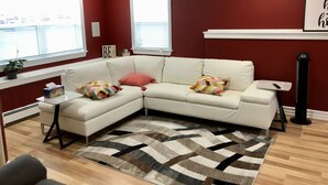 A modern living room with a white sectional sofa, a patterned rug, and red walls.