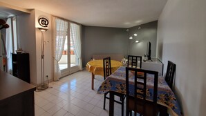 Un espacio habitable compacto con comedor, sofá, una mesita y televisor.