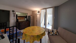 Un espacio habitable compacto con una mesa de comedor, un sofá y una zona de cocina.