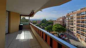 Un balcón con vista a un paisaje urbano, que incluye edificios y árboles.