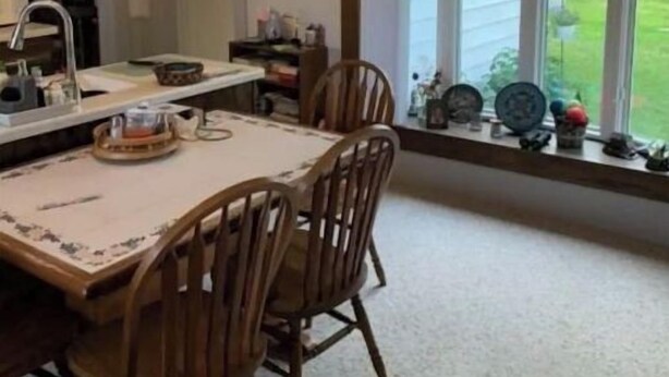 A dining area with a table and chairs, a window with a view of the outdoors, and a kitchen area with a sink and cabinets. - Oak Meadow Farmhouse (Spring Valley)