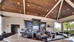 A bar area with a marble countertop, wooden ceiling, and large windows. - Resort Style Living (Bradenton)
