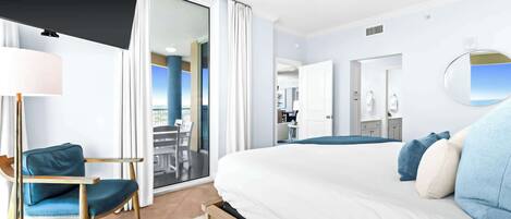 A hotel room with a large bed, a desk, a chair, a lamp, and a view of the outside.