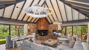 Un salón espacioso con chimenea de piedra, un sofá grande color gris y un televisor.