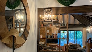 Una sala de estar acogedora con un espejo grande, una decoración de cabeza de ciervo y un techo de madera rústica.