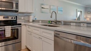 A modern kitchen with stainless steel appliances, white cabinetry, and a large island with a sink.