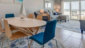 A spacious living room with a round table, blue chairs, a sofa, and a ceiling fan.
