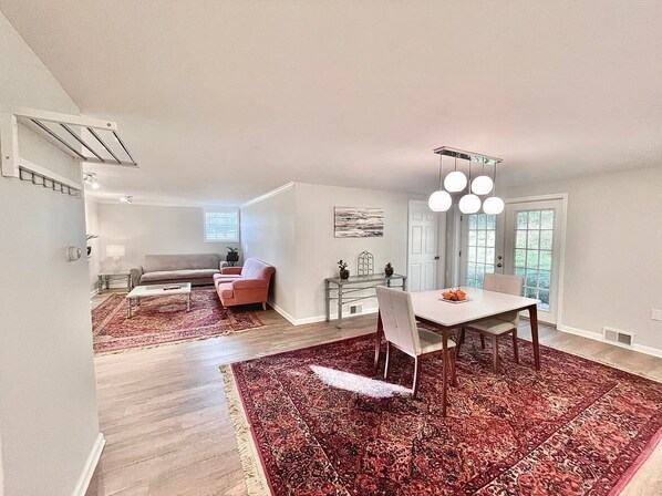 A spacious living area with a dining table, a sofa, and a red patterned rug. - Luxury Hideaway on Serene and Private Acreage (Avonmore)