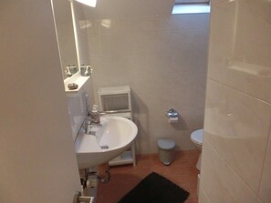 Un baño pequeño con lavamanos, inodoro y un ventanal.