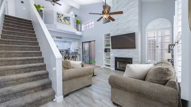 A spacious living area with a staircase, two sofas, a flat-screen TV, and a fireplace. - Private condo near Mayo Clinic with garage, patio, office, and pool access.  (Scottsdale)