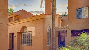 A courtyard with a building featuring a tiled roof, arched windows, and a palm tree. - Private condo near Mayo Clinic with garage, patio, office, and pool access.  (Scottsdale)