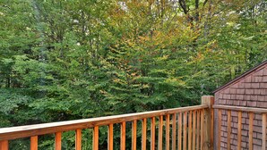 A wooden deck with a view of dense forest. - Charming Glazebrook Condo - 1 Mile to Lifts - Close to everything! J3 (Killington)