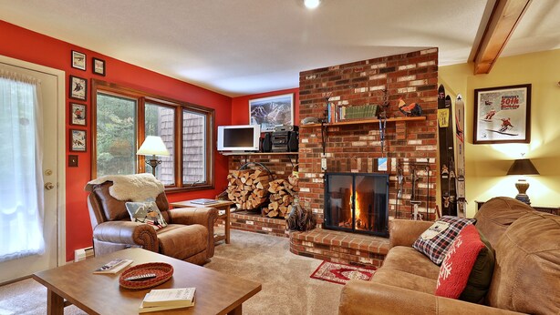 A cozy living room with a brick fireplace, leather furniture, and a television. - Charming Glazebrook Condo - 1 Mile to Lifts - Close to everything! J3 (Killington)