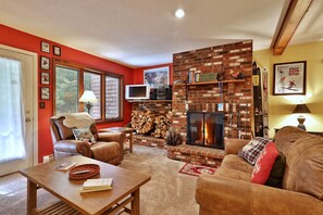 Una sala de estar acogedora con chimenea de ladrillo, muebles de cuero y televisor.