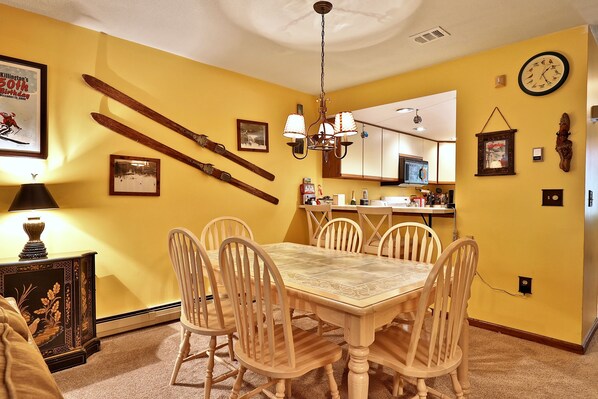 Un comedor con una mesa y sillas de madera, una araña y decoración con temática de esquí.