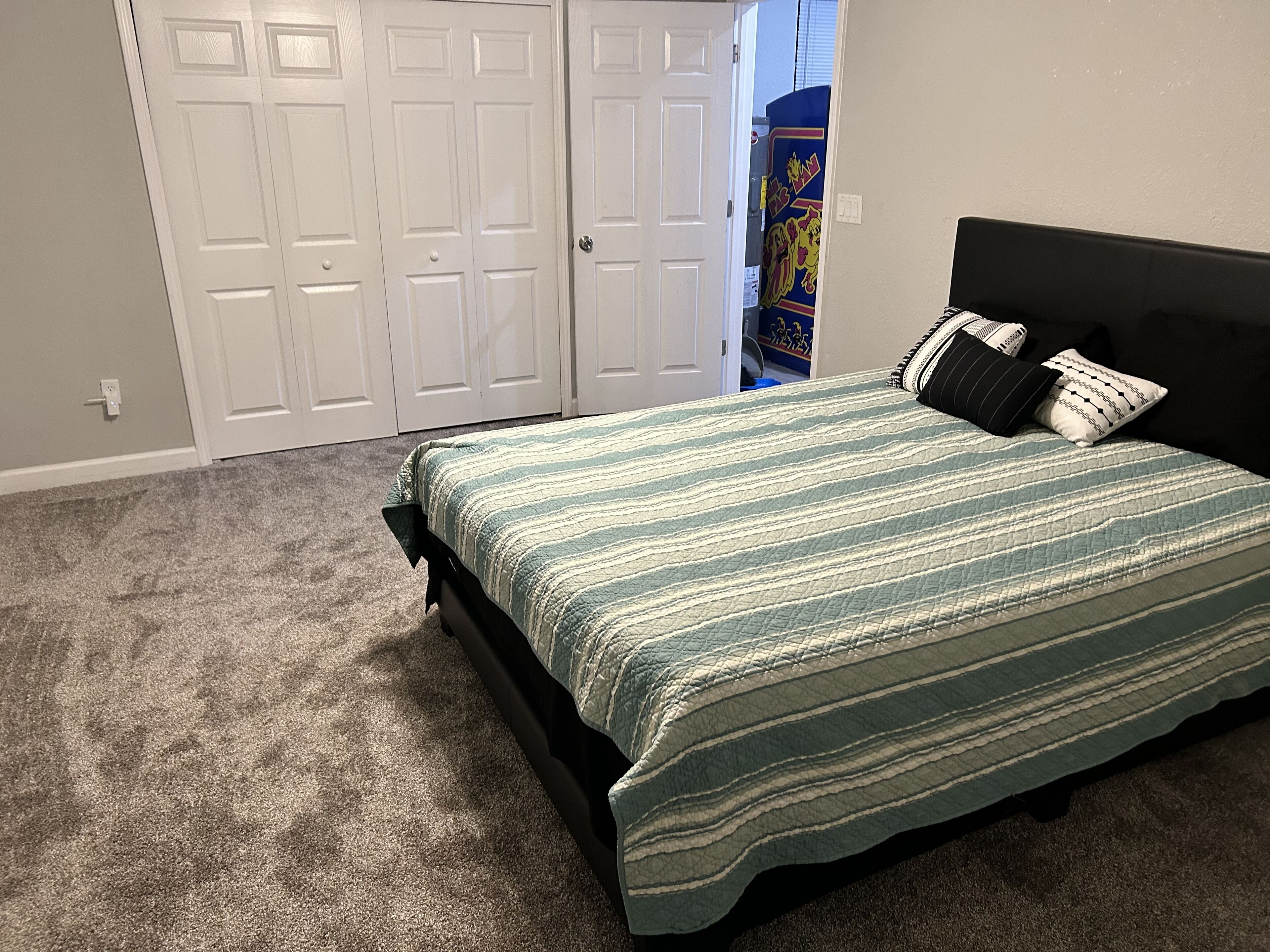 A bedroom with a bed, a headboard, and a carpeted floor.