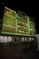 Un hotel de varios pisos con un letrero llamativo que dice "The Venetian Hotel, Banquets, Lawns, Restaurant".