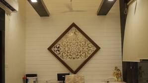 Un comedor con una lámpara moderna, un adorno en la pared y una mesa con sillas estampadas.